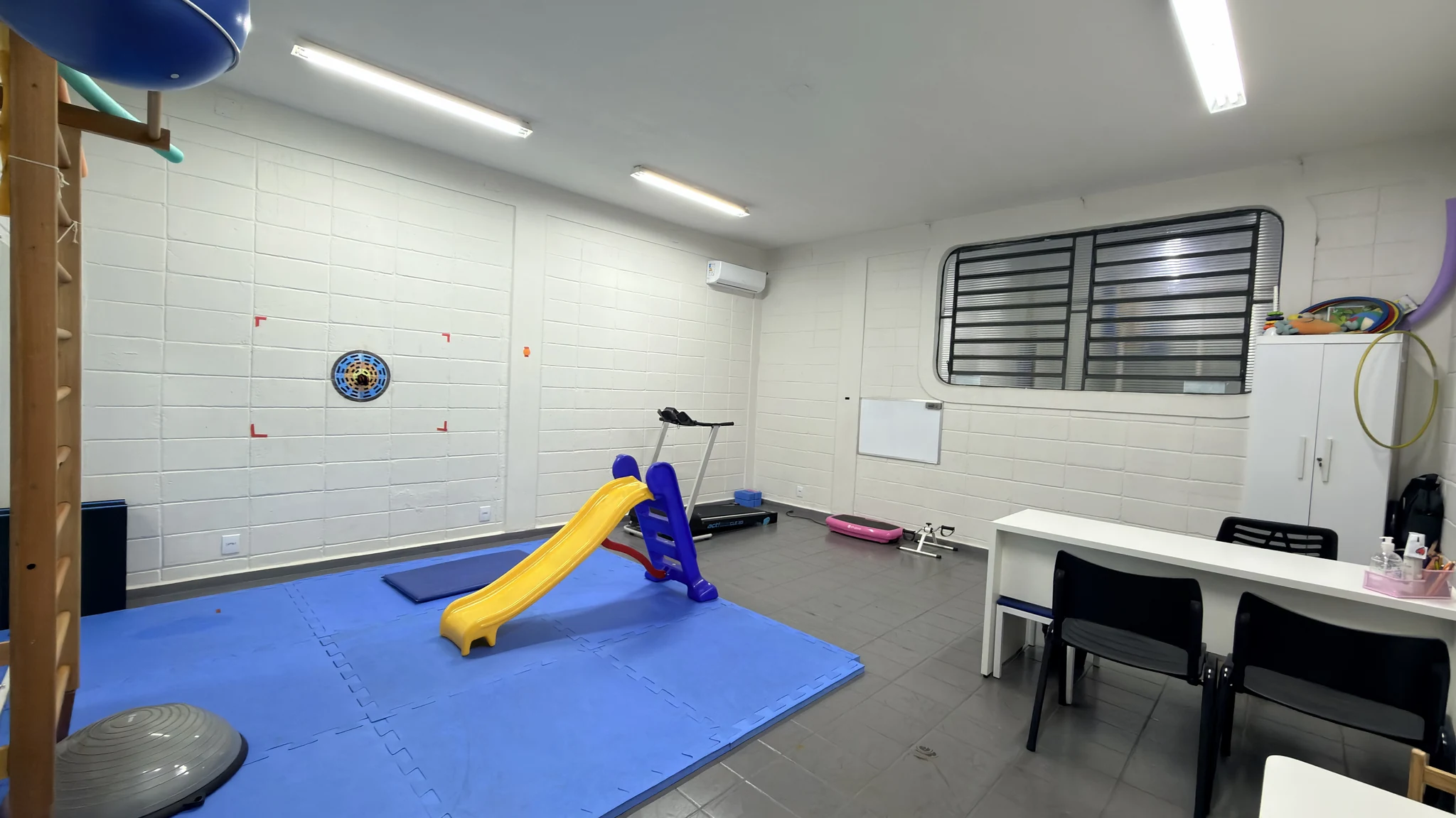 Sala de psicomotricidade com escorregador, esteira e circuito motor